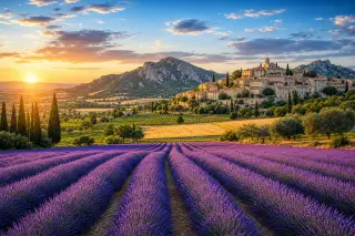 Lavender fields and vineyards with a perched stone village, golden hour light, the Alpilles mountains in the background, Provençal countryside.